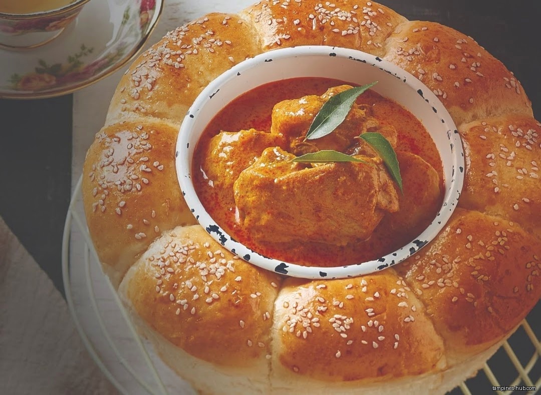 A bread ring surrounds a bowl of curry, with a teacup nearby.