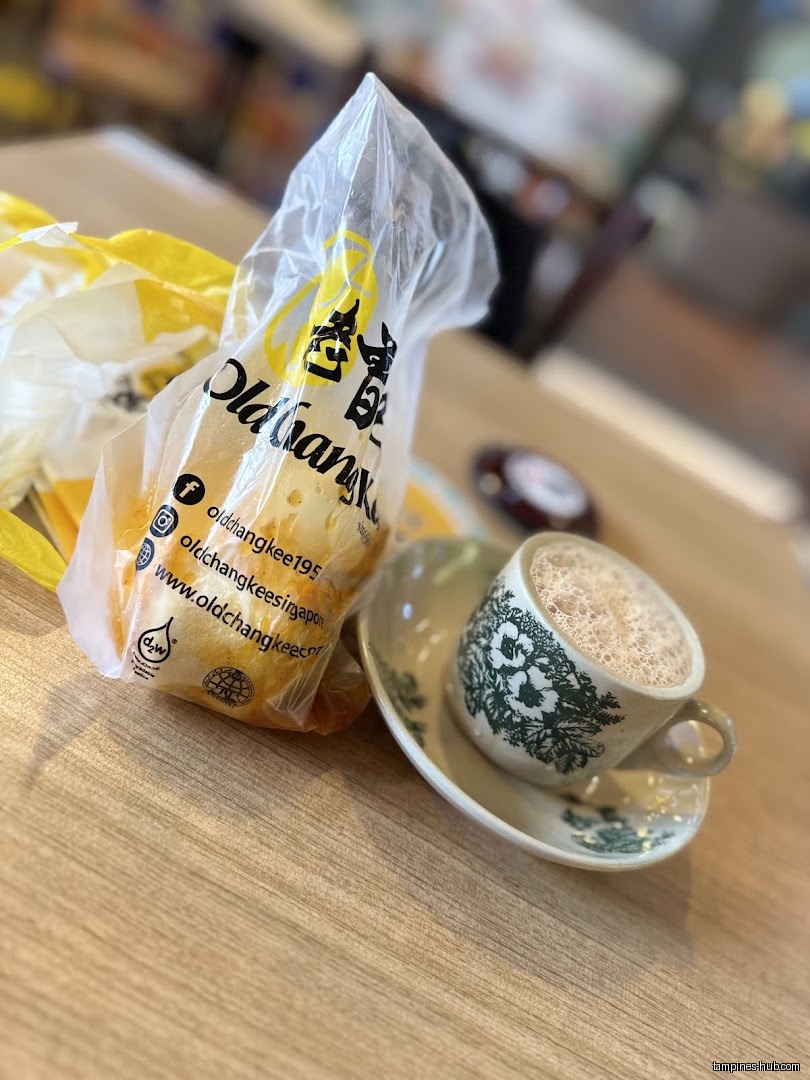 Old Chang Kee snack in a bag and a cup of coffee on a table.