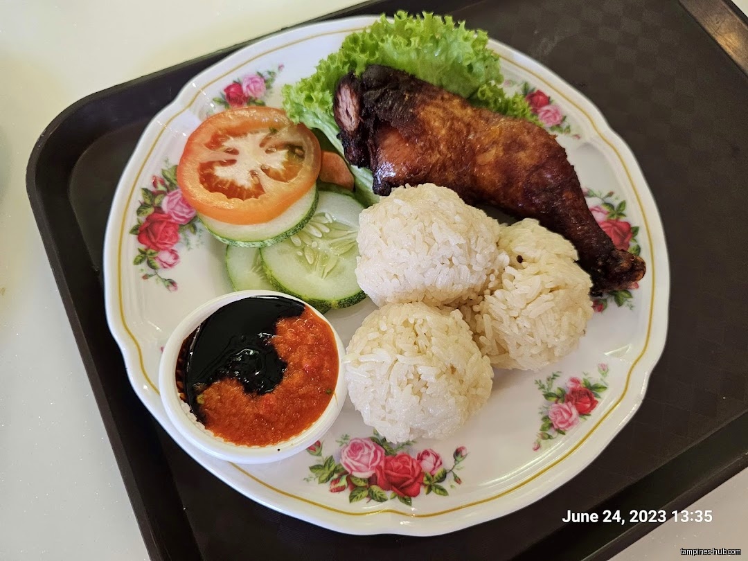 A plate of chicken rice with vegetables and chili sauce is shown.