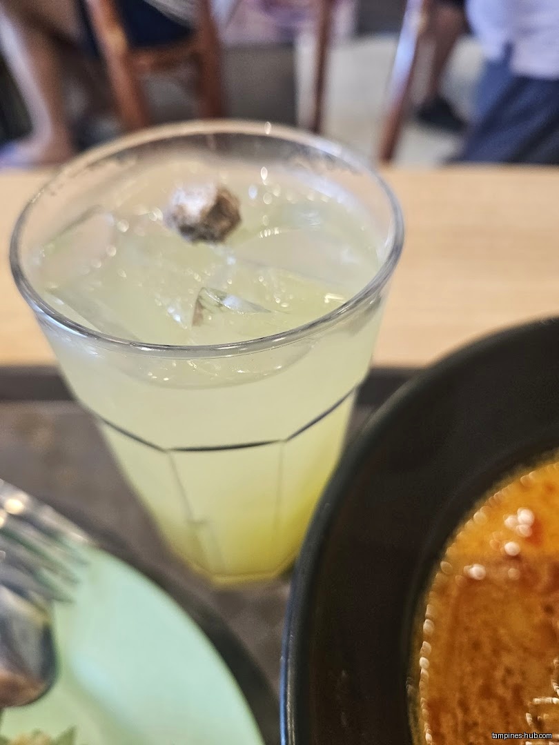 A glass of iced drink and a bowl of food on a table.
