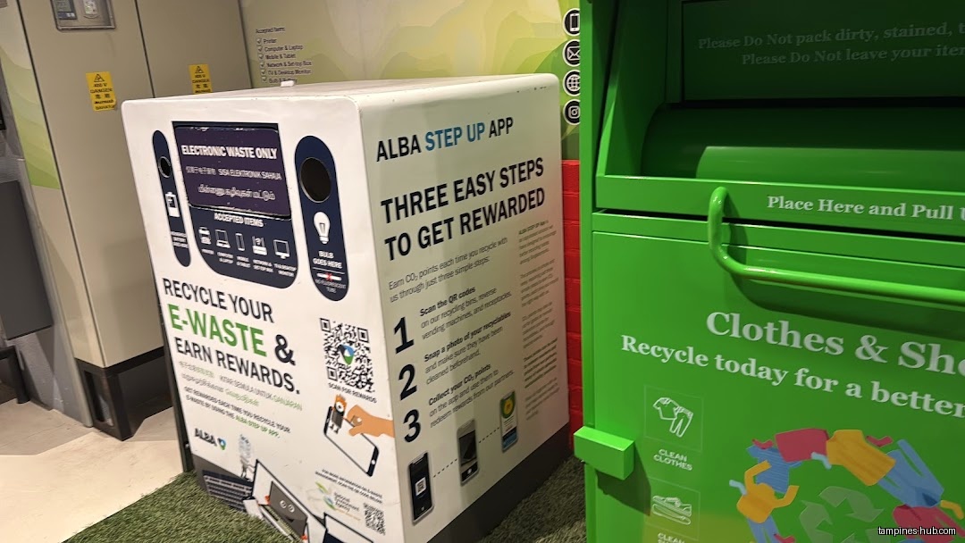 The image shows recycling bins for e-waste and clothes/shoes in a shop.
