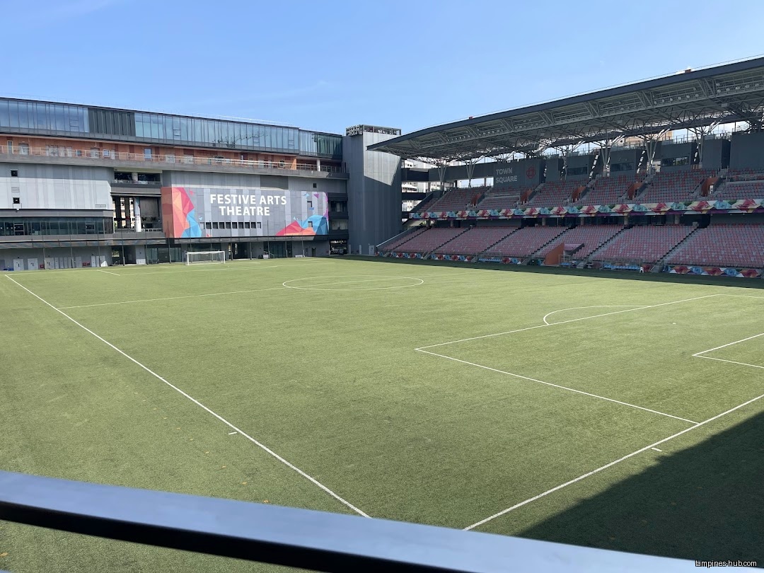 The image shows a soccer field with stadium seating and a building.