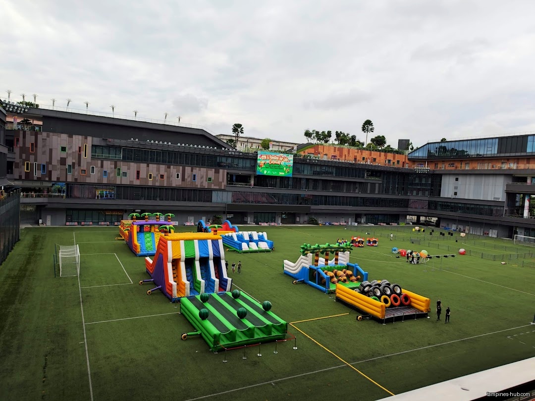 The image shows inflatable obstacle courses set up on a green field.