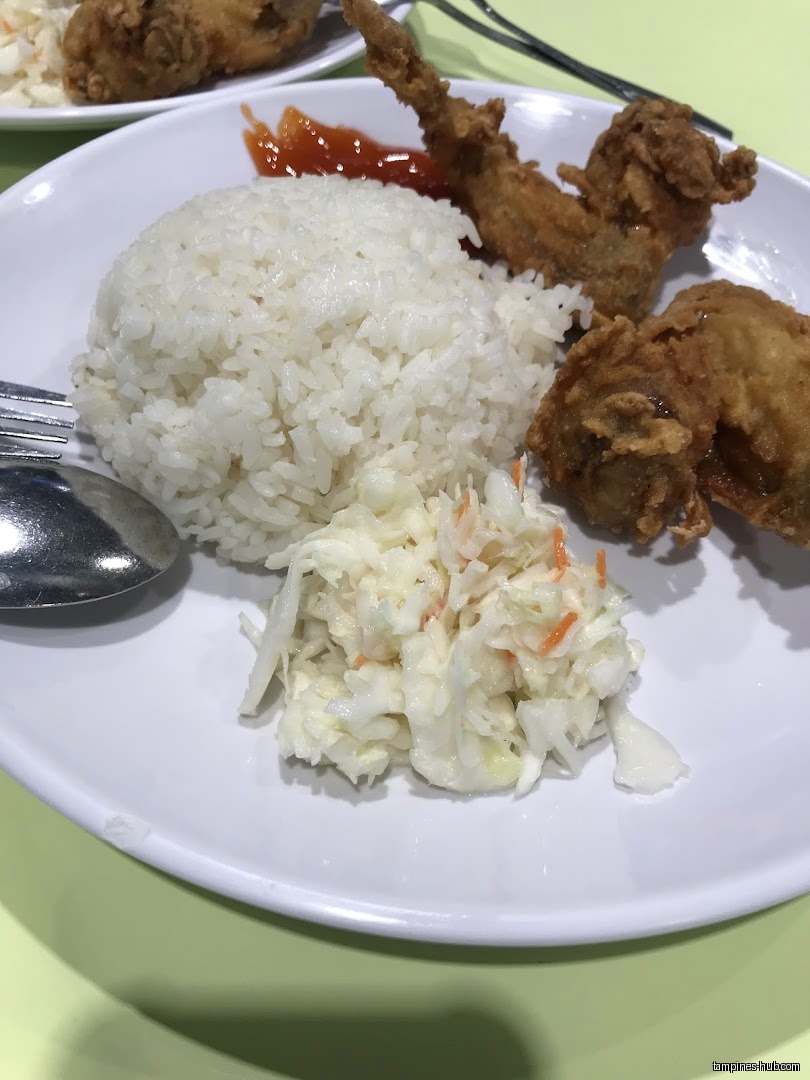 A plate of rice, coleslaw, fried chicken, and chili sauce is shown.