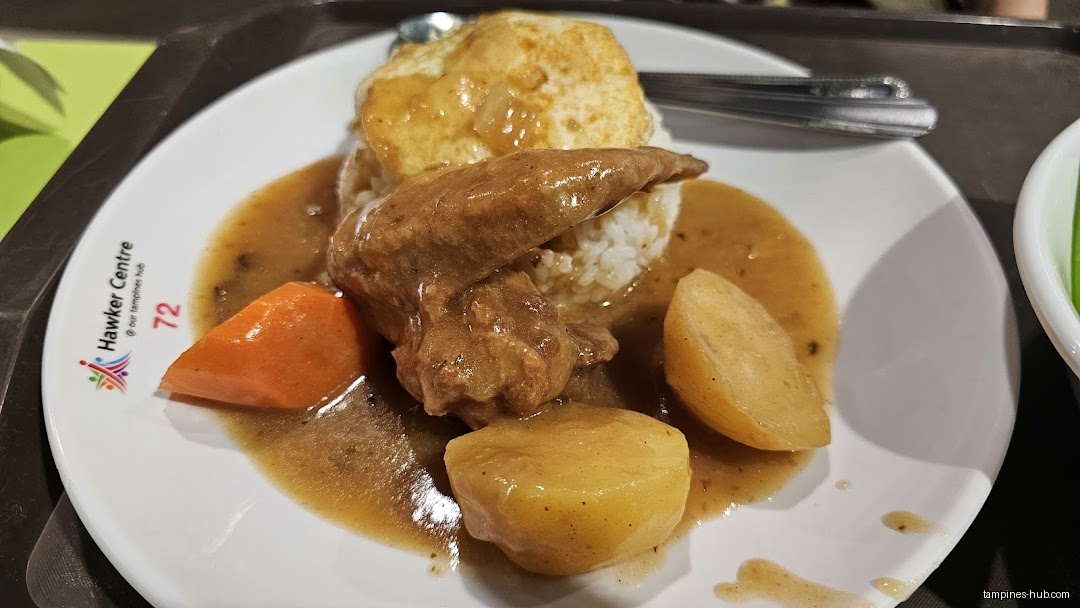 A plate of rice, chicken, egg, potatoes, and carrots with gravy.