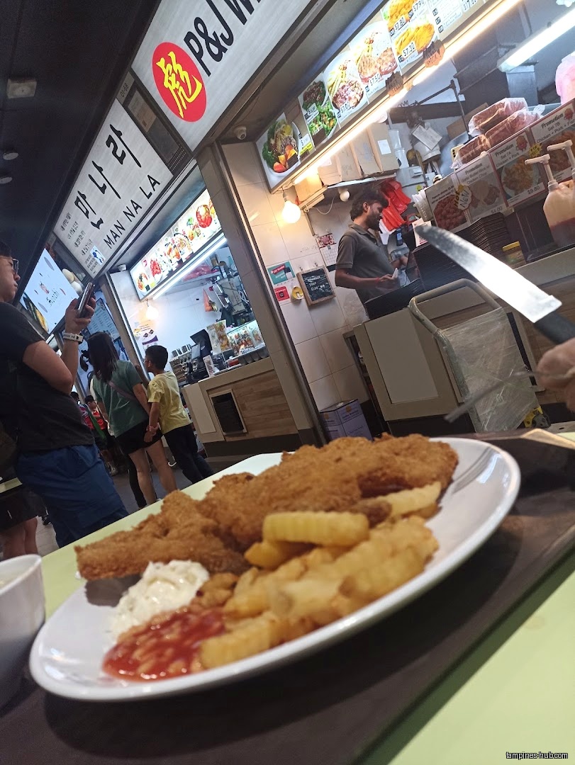 A plate of fish and chips is shown in front of food stalls.