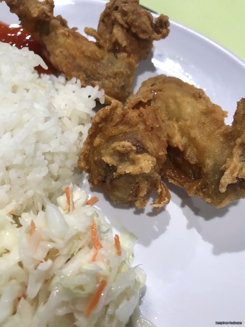 A plate of fried chicken, rice, coleslaw, and sauce is shown.