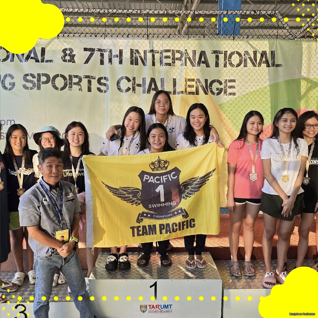 A swim team poses on a podium with a team banner.