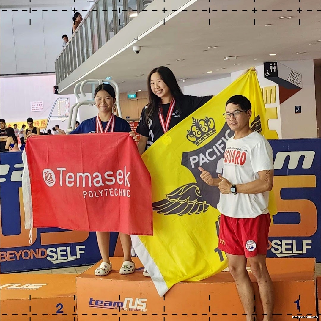 Three people on a podium holding flags, likely after a swimming competition.