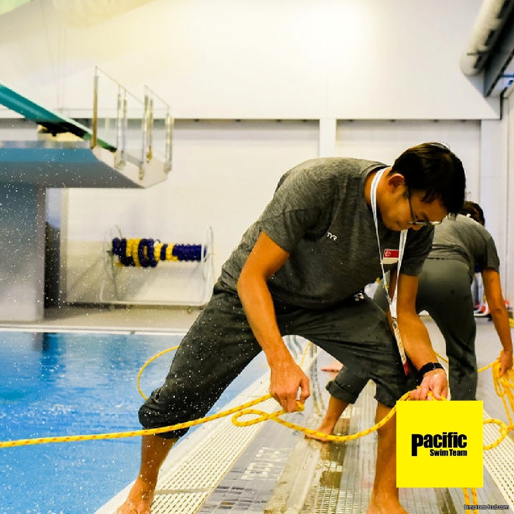 A man is holding a rope near a swimming pool.