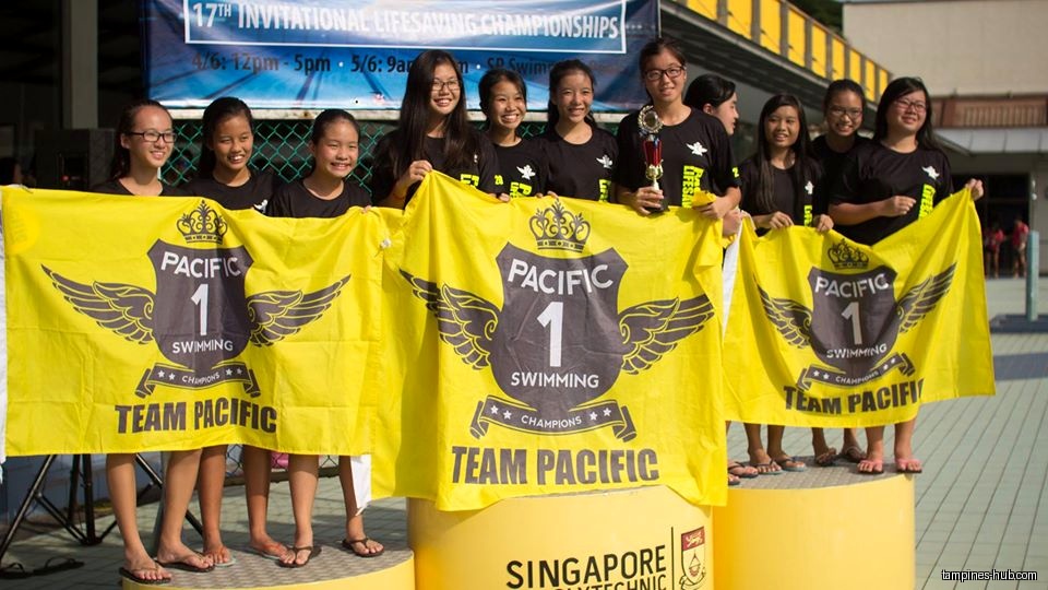 A group of girls hold a banner for Pacific Swimming Team after winning.