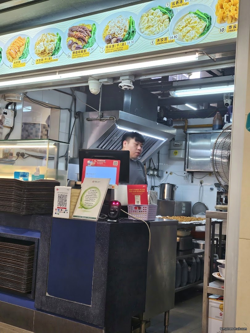Pang Pang Wanton Noodle shop interior with a worker and menu board.