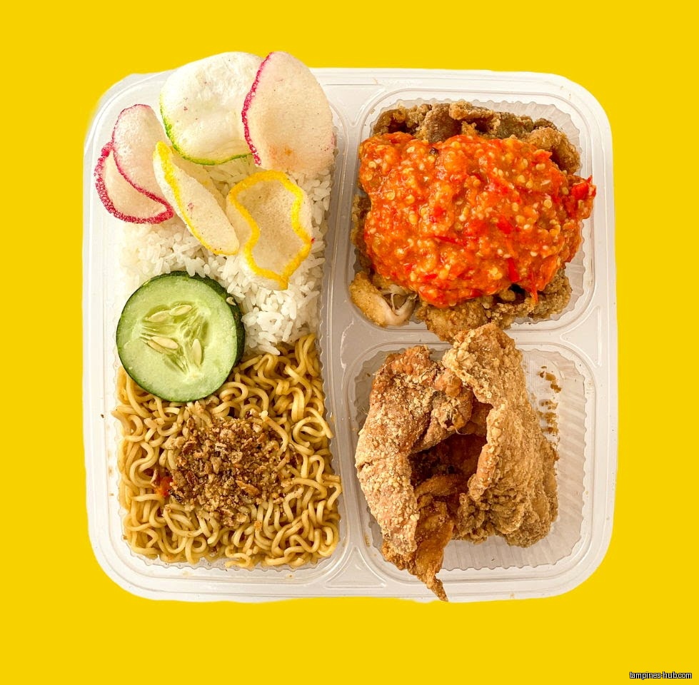 A container of food with rice, noodles, fried chicken, and chili sauce.