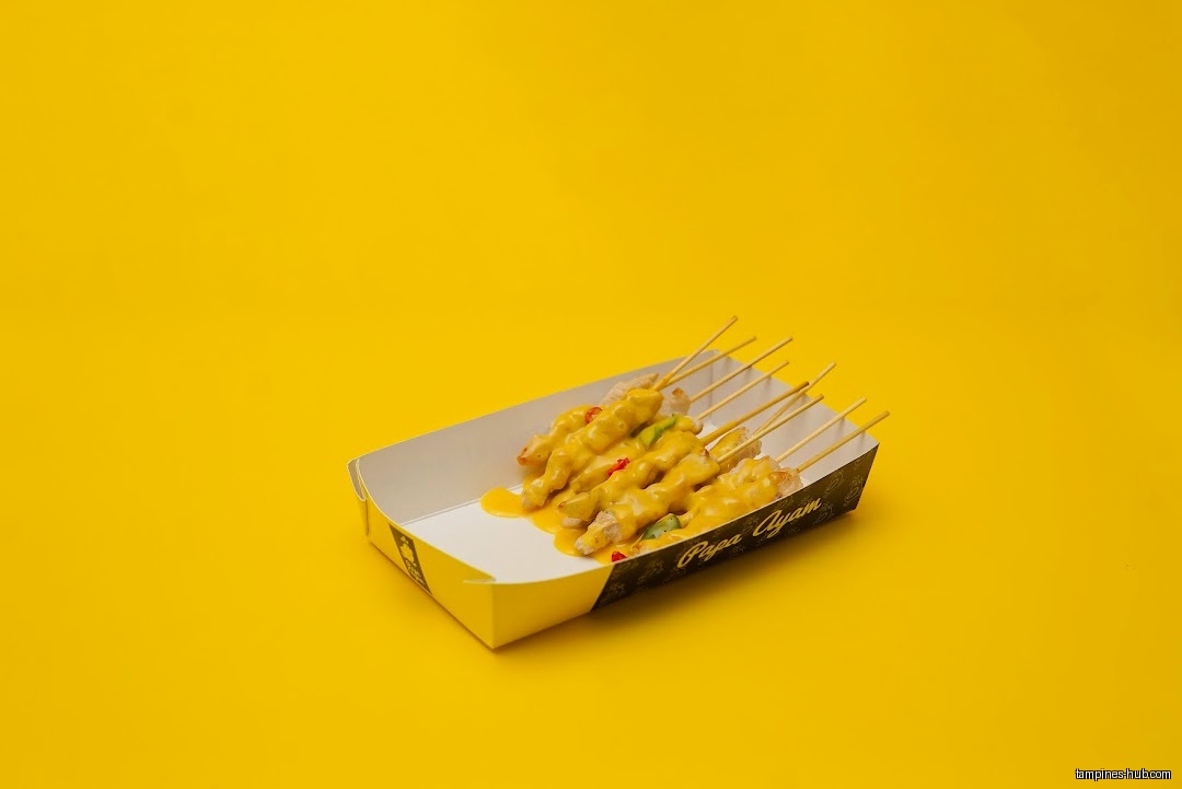 Papa Ayam chicken satay skewers with sauce in a paper tray.