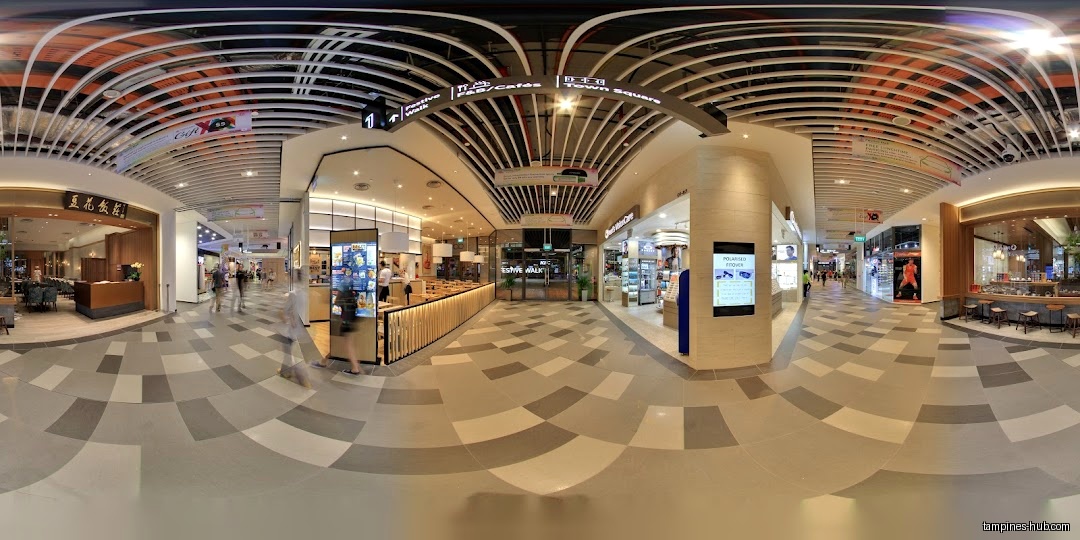 A wide-angle view of a shopping mall interior with various shops.