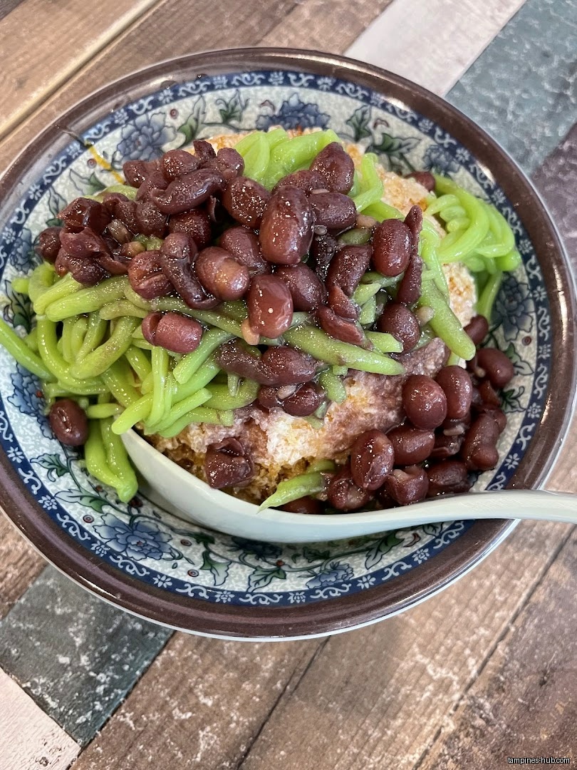 A bowl of cendol with red beans and green jelly noodles.