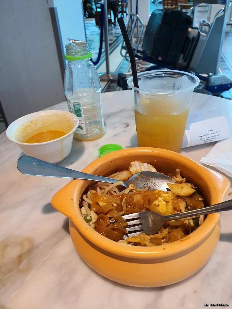 A bowl of noodles, a drink, and a bottle on a table.