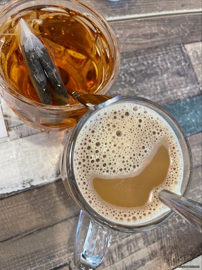 Overhead shot of tea and a foamy beverage on a wooden table.