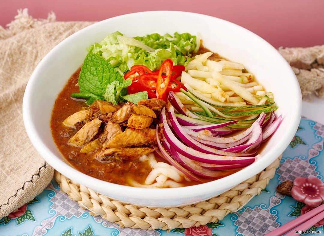 A bowl of Penang Laksa with noodles, fish, and vegetables.