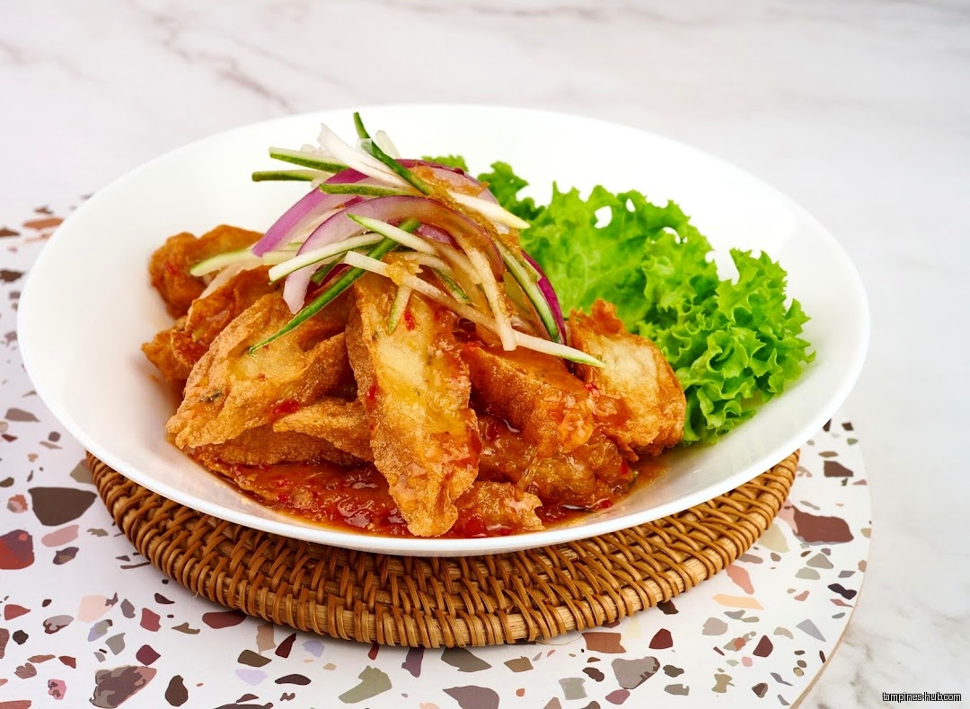 A plate of fried fish with sauce and vegetable garnish.