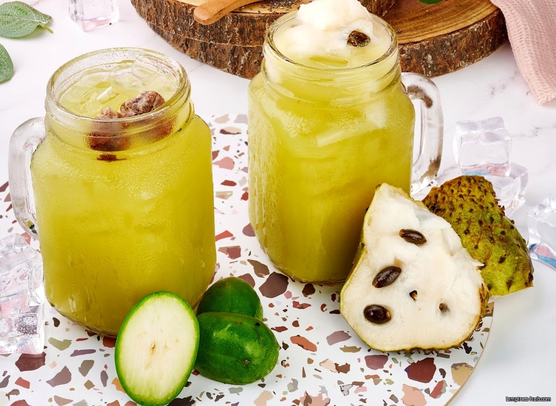 Two glasses of green juice with fruit and ice on a table.