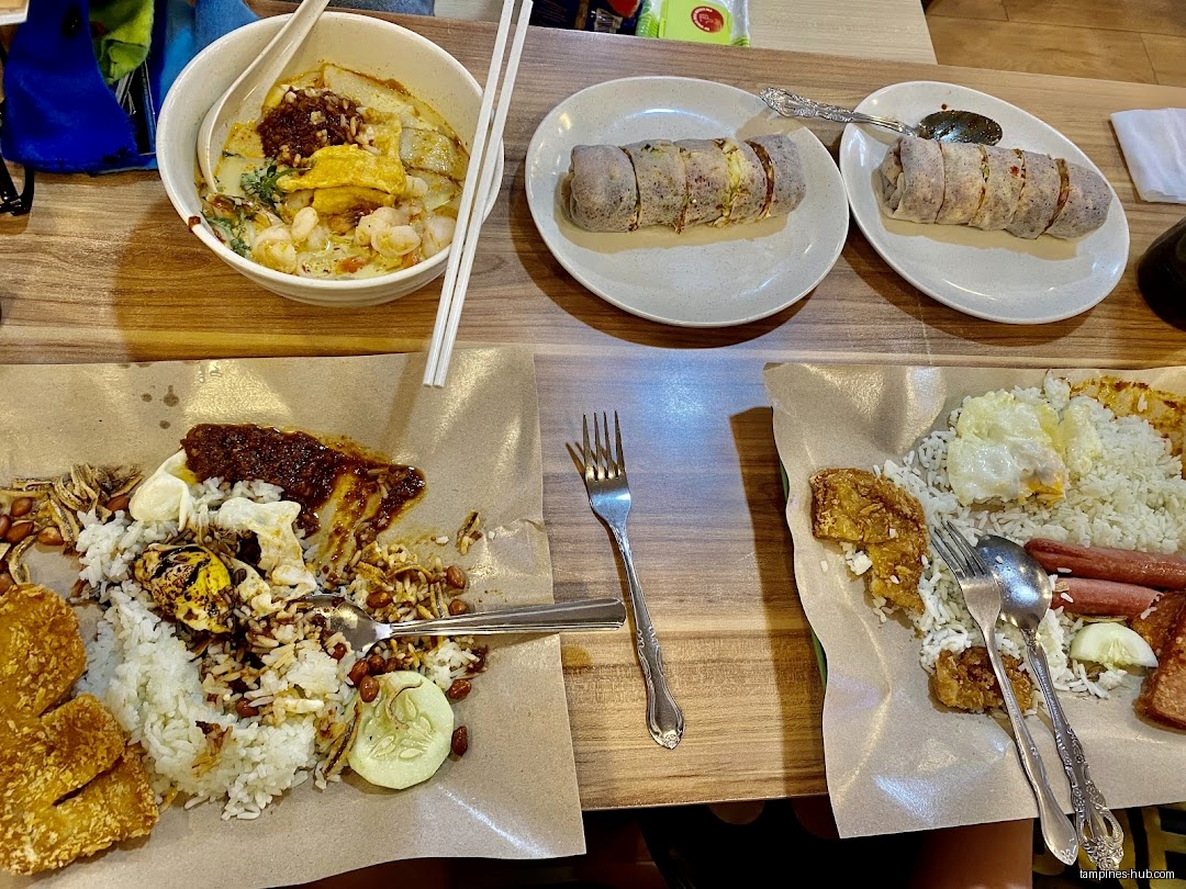 The image shows a table with various dishes of food, including Nasi Lemak.