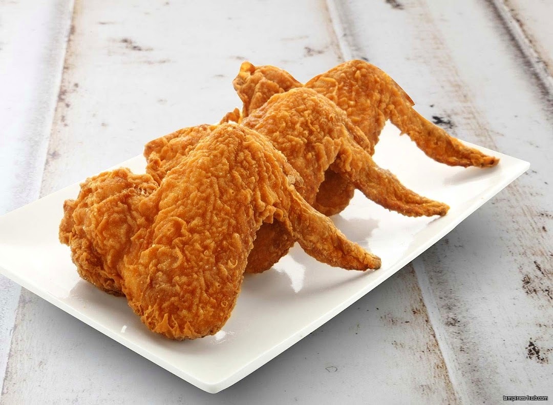 A white plate holds three golden-brown, crispy fried chicken wings.
