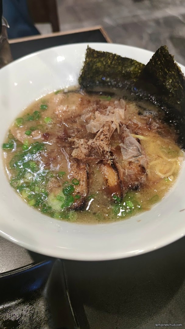 A bowl of ramen with seaweed, green onions, and other toppings.