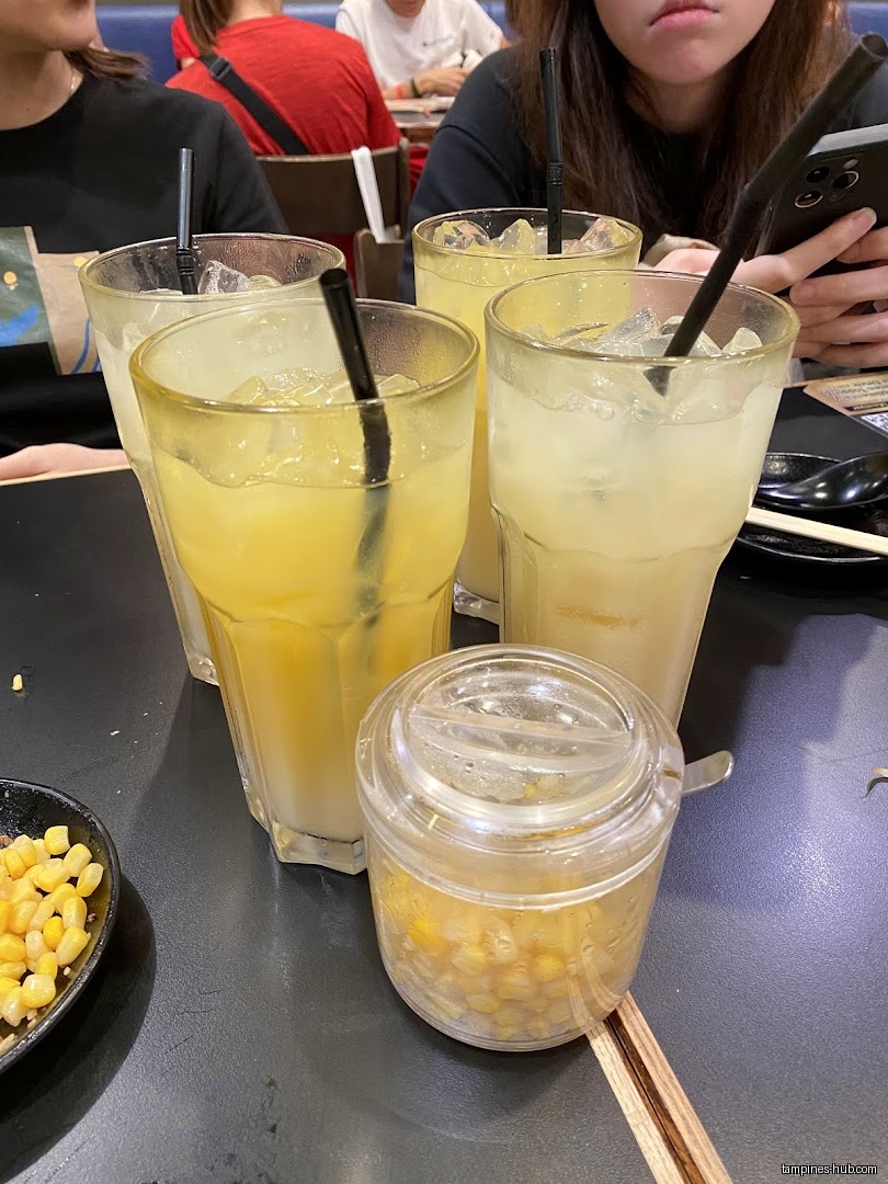 Four drinks with ice and a container of corn on a table.