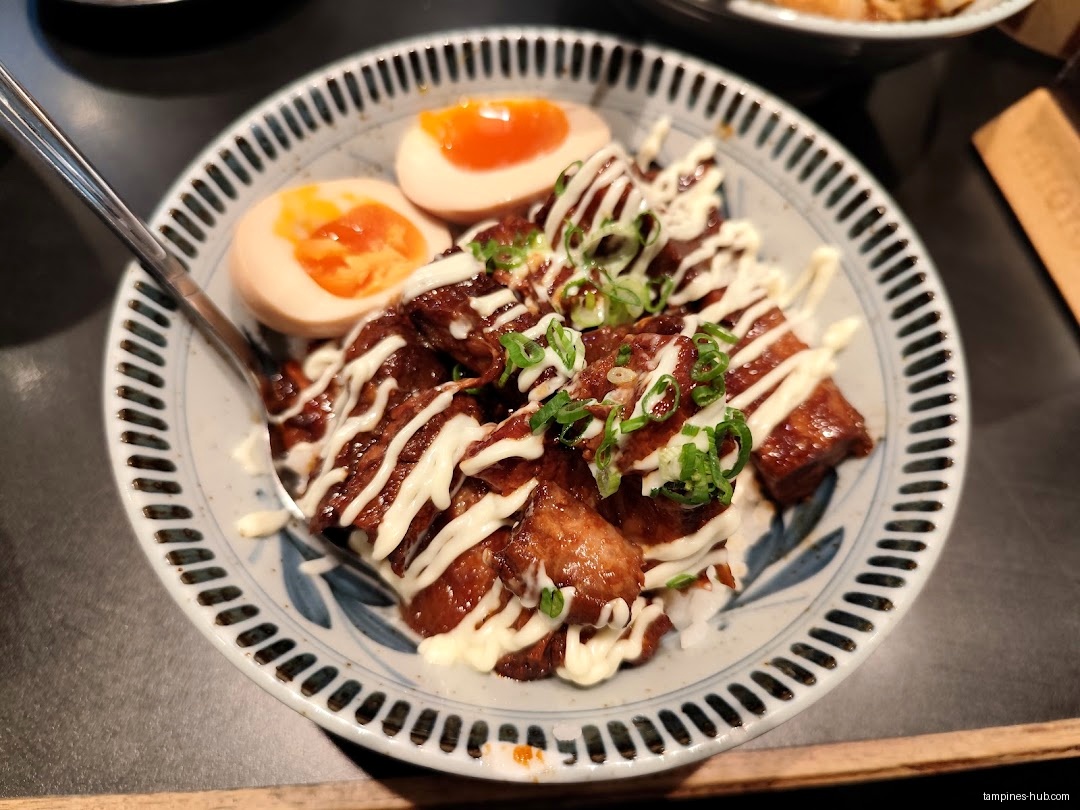 A bowl of rice topped with meat, sauce, and soft boiled eggs.