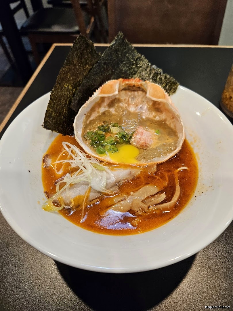 A bowl of ramen with a crab shell and seaweed on top.