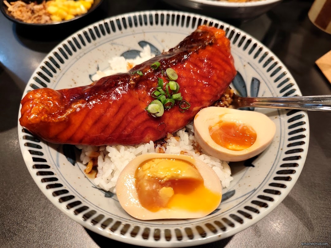A bowl of rice topped with salmon and soft-boiled eggs.