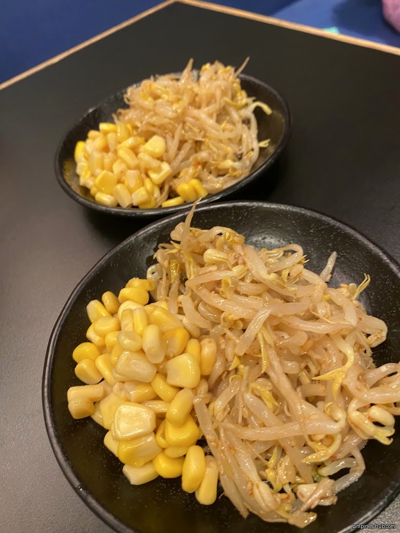 Two small black bowls filled with corn and bean sprouts are shown.