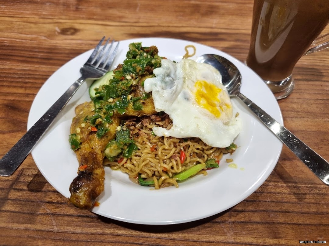 A plate of noodles with chicken, egg, and a drink on a table.