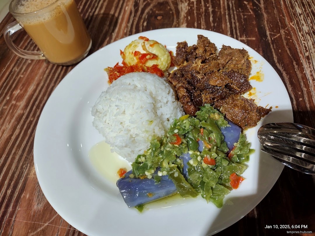A plate of rice, meat, vegetables, egg, and a drink on a table.