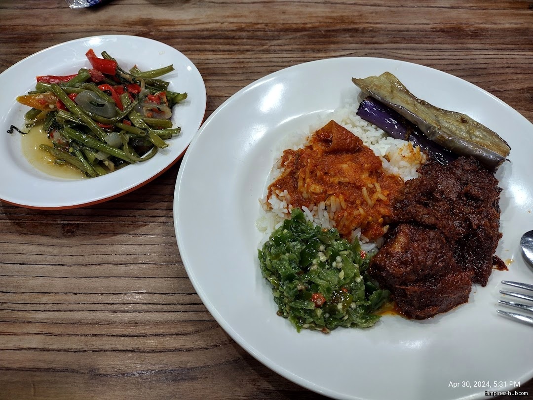 A plate of rice with various dishes and a side of vegetables.