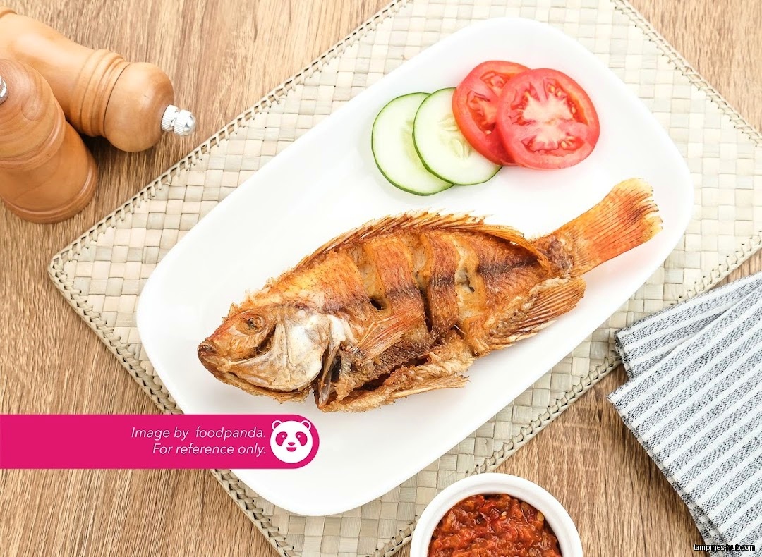 A fried fish is served with cucumber and tomato slices on a plate.