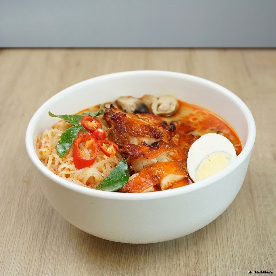 A bowl of Thai noodles with chicken, egg, and chili peppers.