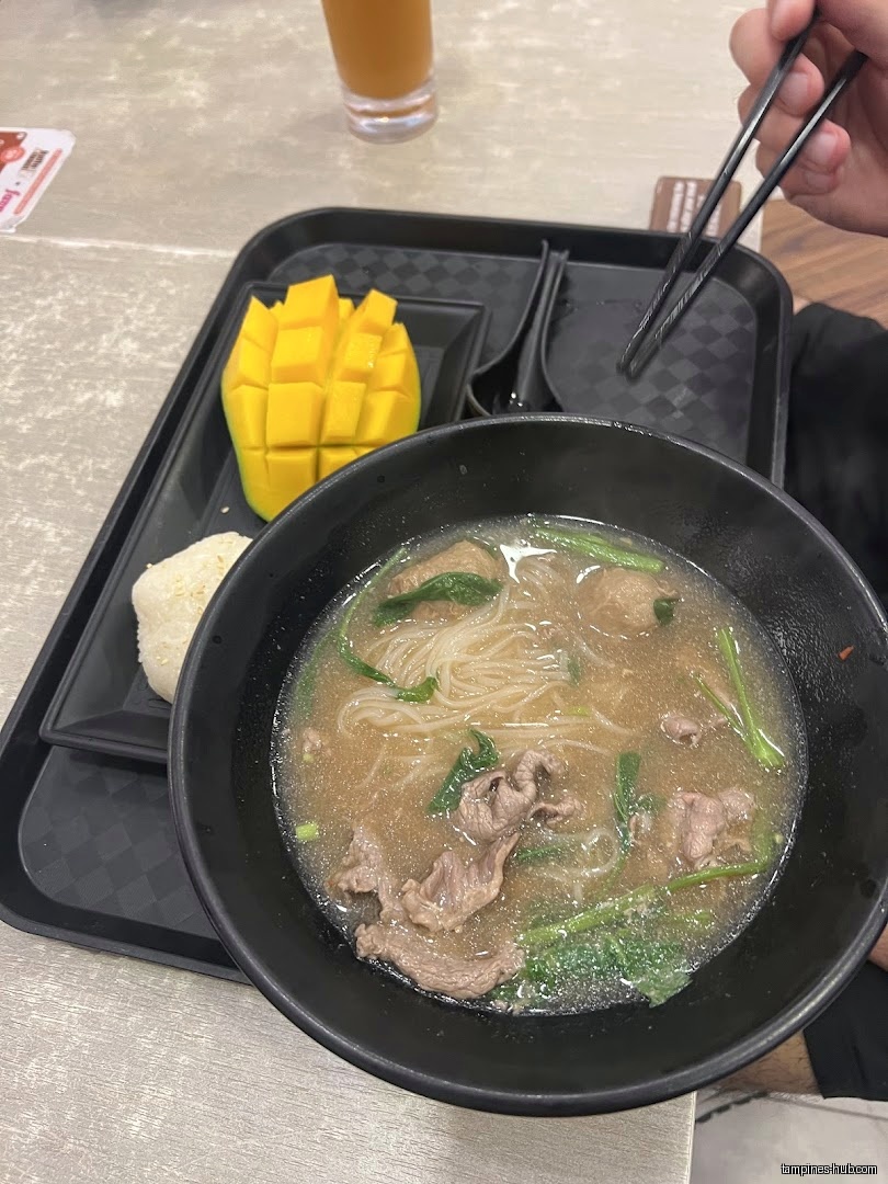 A tray with noodles, mango, rice, and a drink is visible.