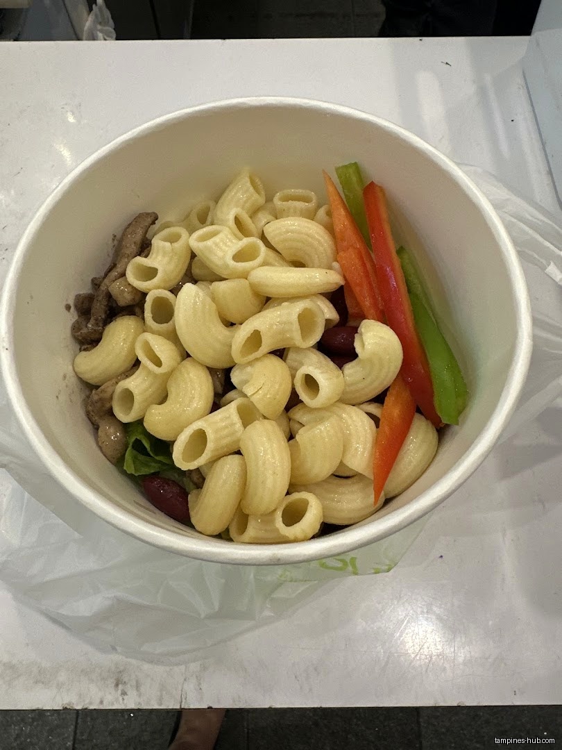 A bowl of pasta salad with meat, beans, and vegetables.