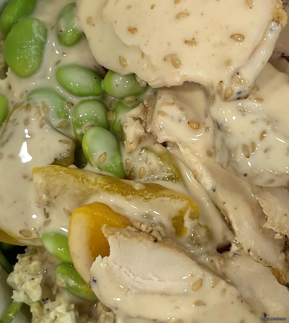 Close-up of a salad with chicken, edamame, and a creamy dressing.