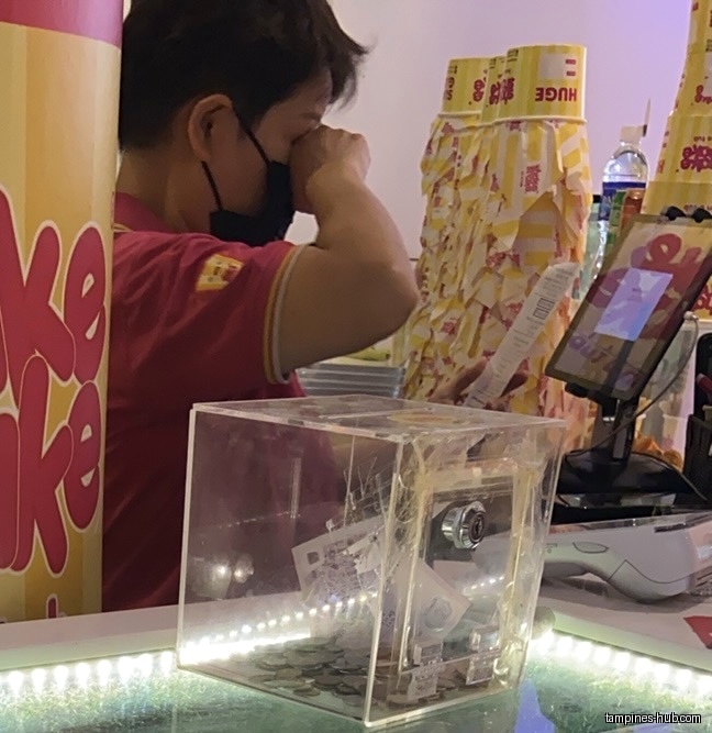 A staff member is at the counter with a cash box.