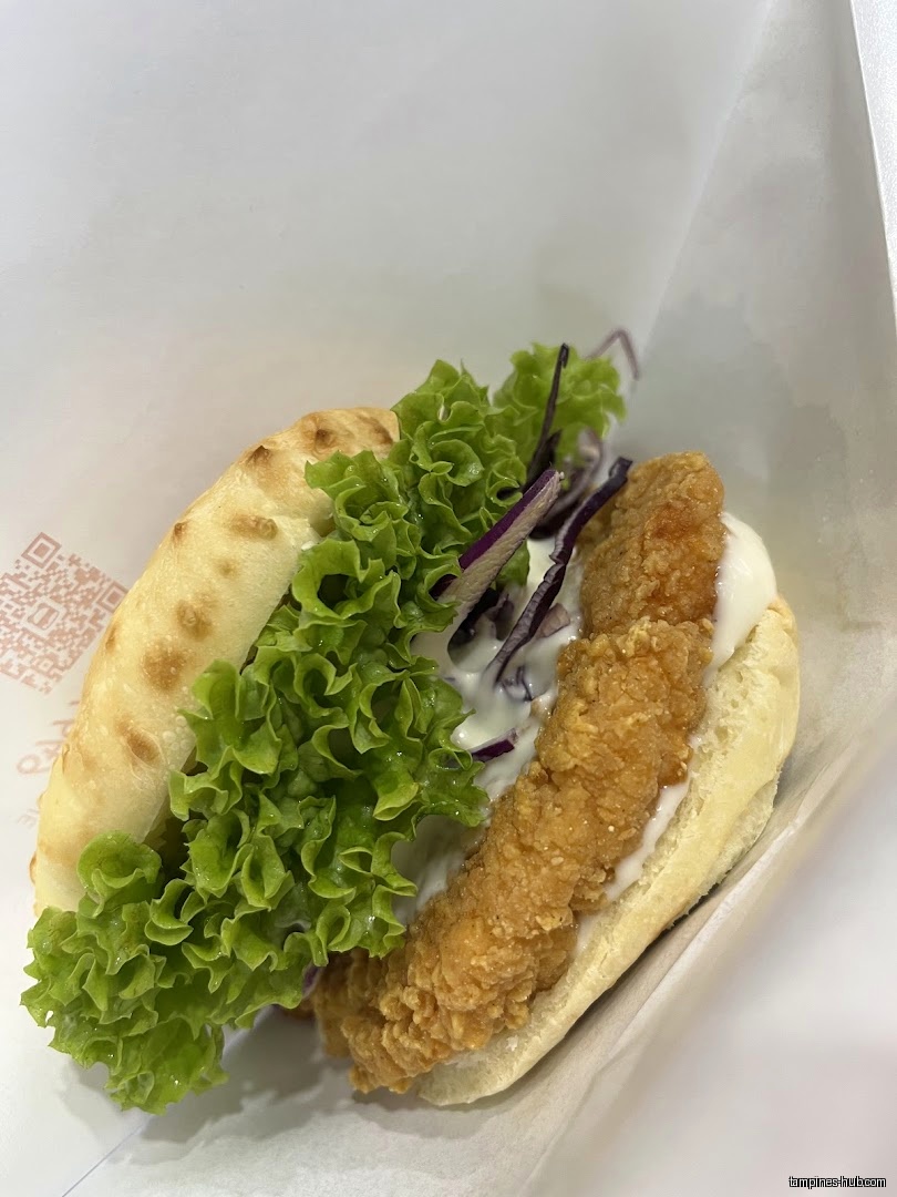 A close-up shot of a burger with fried chicken and lettuce.