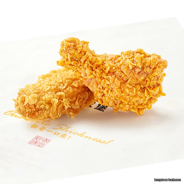Two pieces of fried chicken on a branded paper sheet.