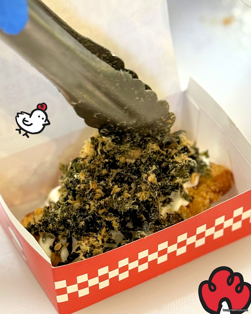 A fried food item topped with seaweed and floss in a red box.