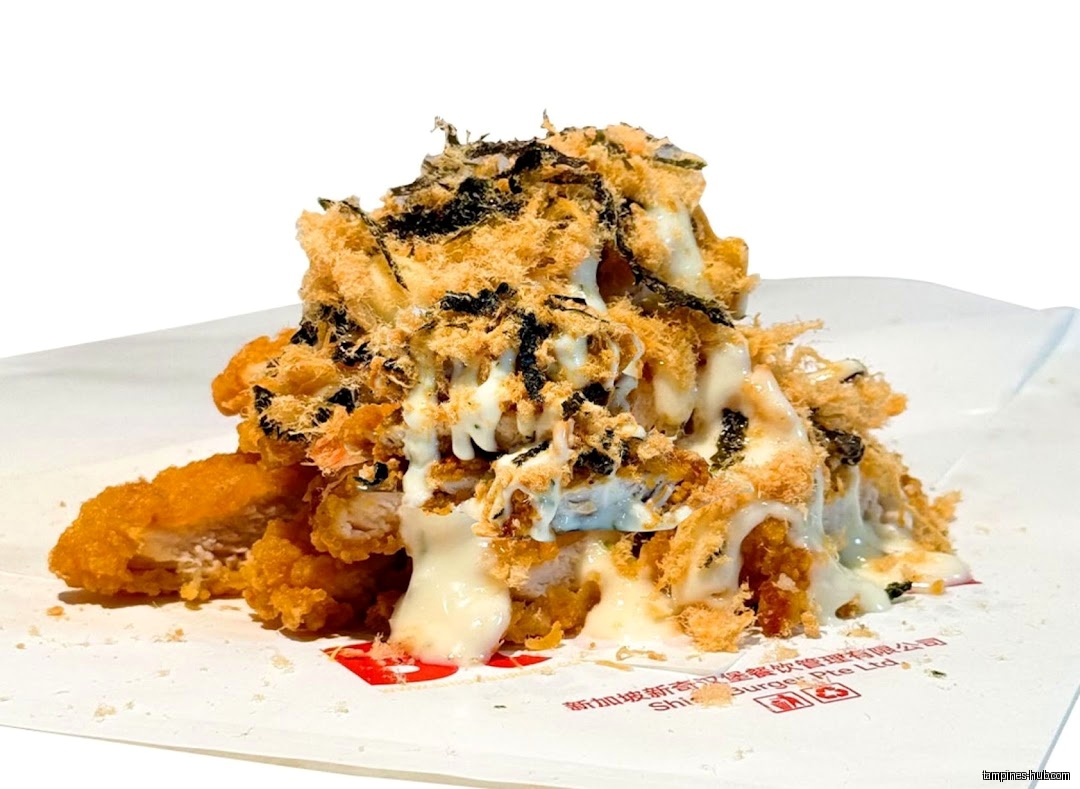 A close-up shot of fried chicken topped with seaweed, floss, and sauce.