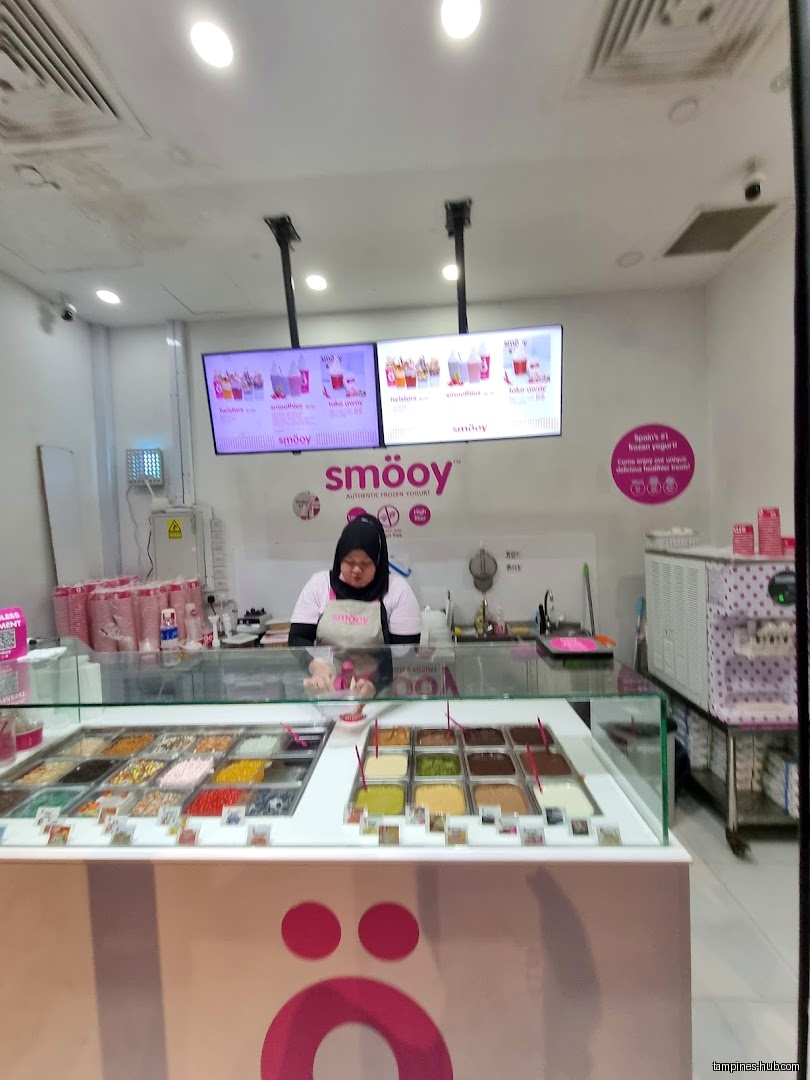 A smöoy shop interior with a worker and toppings bar.