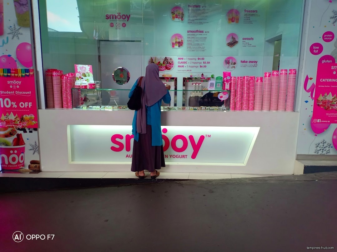 A customer stands at the counter of a Smöoy frozen yogurt shop.
