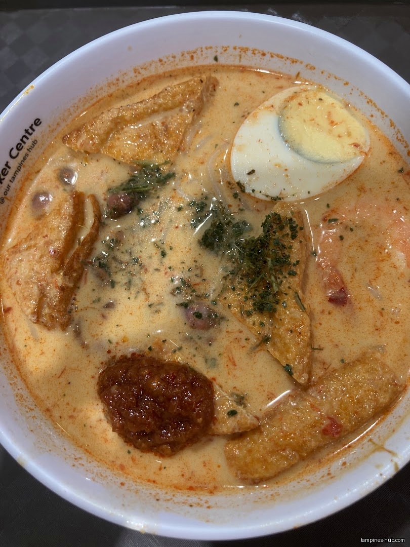A bowl of Laksa soup with tofu, egg, and other ingredients.