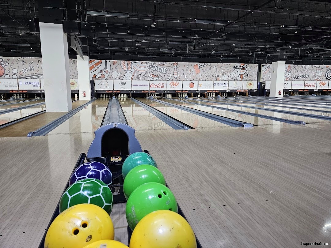 Bowling balls in a rack at Sonic Bowl, with lanes in the background.
